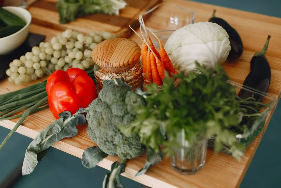Carrots, cabbage, broccoli, peppers, eggplant and herbs on a wooden kitchen board.