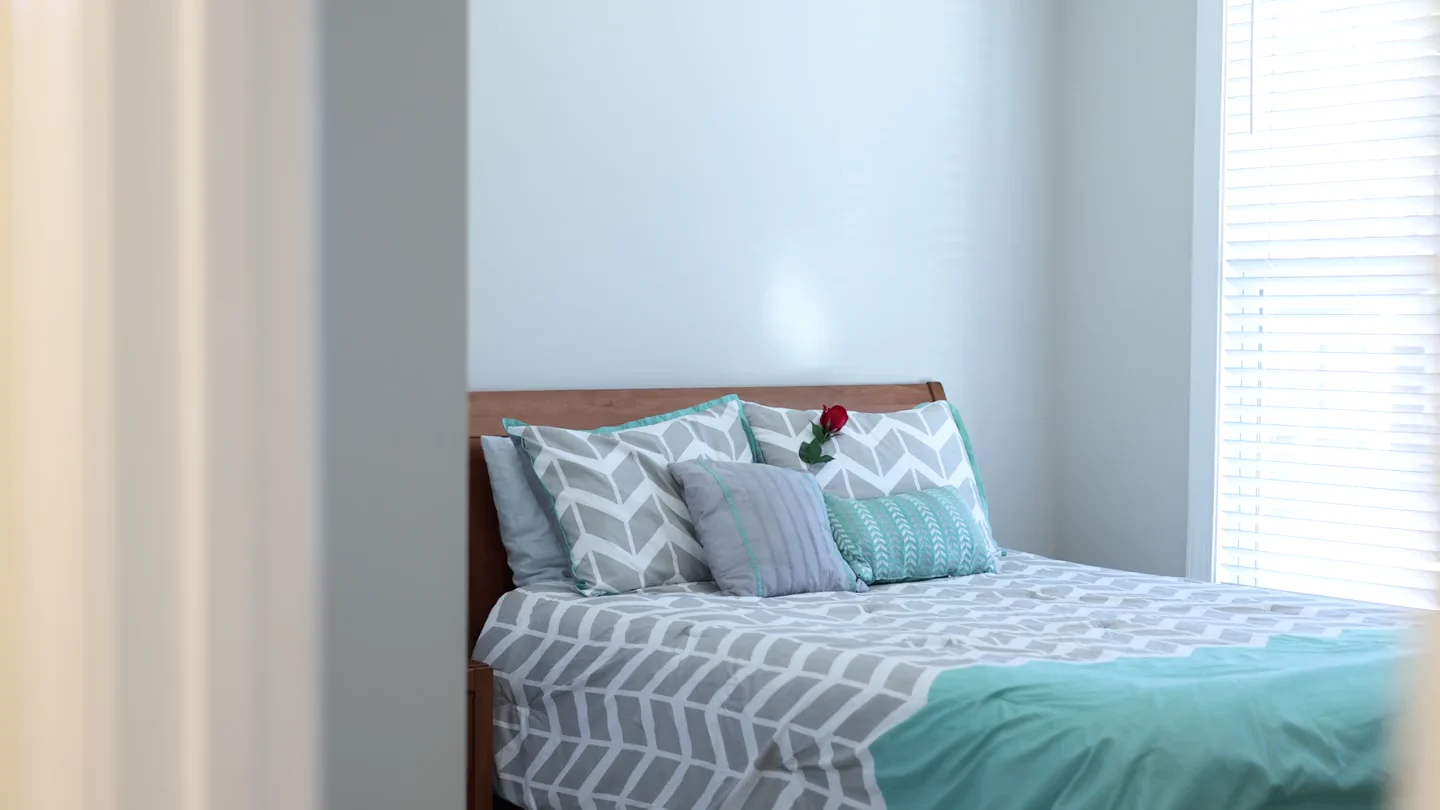 A bright bedroom seen from a doorway beside a light-colored wall.